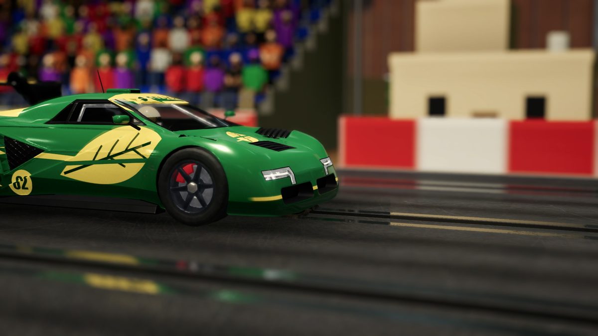 A green car up close in front of a packed grandstand